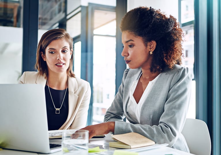 duas mulheres, vestindo roupa social, trabalhando em um escritório.