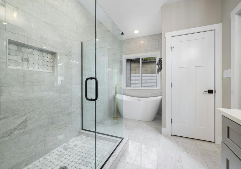 Casa de banho moderna com banheira, revestimento em porcelanato nas paredes e duche de vidro.