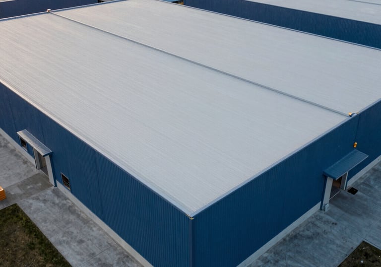 Wide aerial shot of a finished industrial project in North America. A vast warehouse roof with clean architectural lines, finished in Light Gray and Dark Blue tones. The professional setting reflects durability and authority.