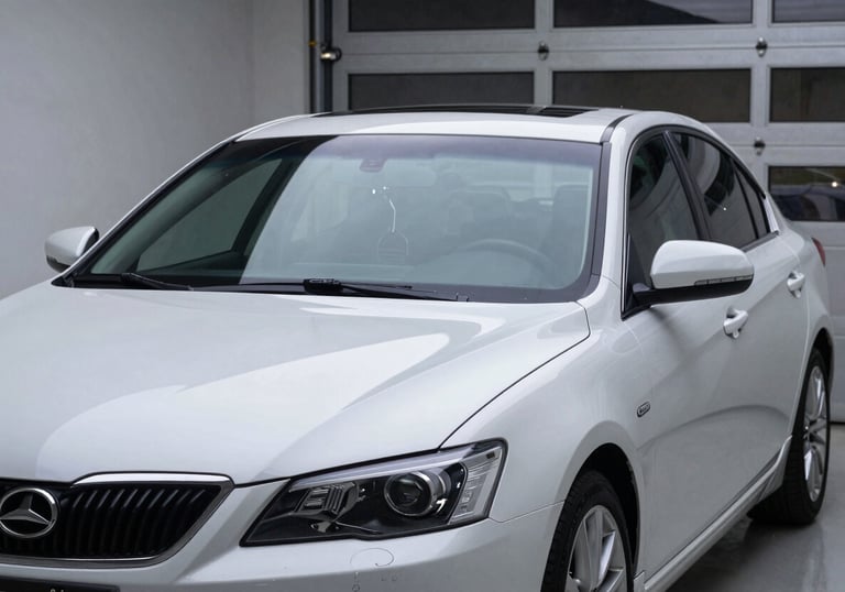 A shiny, perfectly repaired sedan parked in a modern North American garage. The front windshield is crystal clear, catching the light. Professional and high-quality craftsmanship.