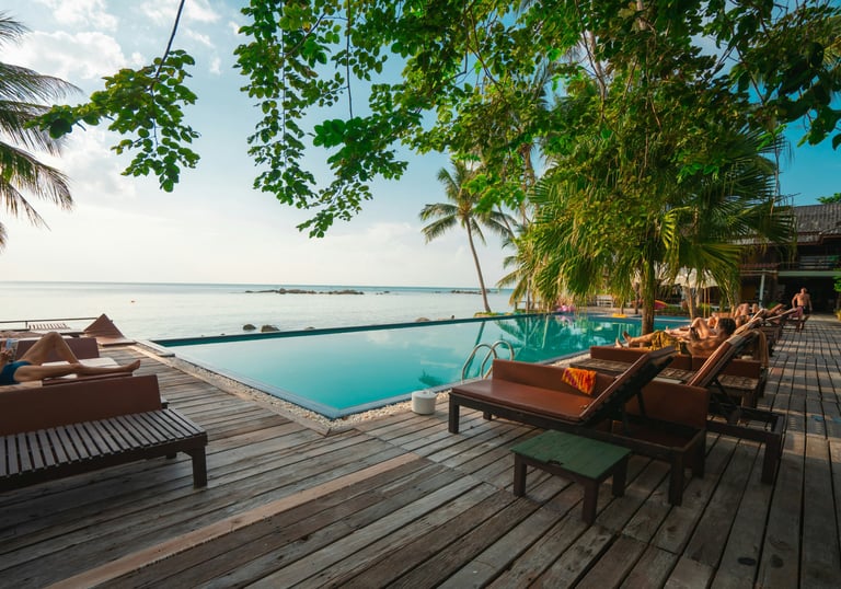 Pool overlooking the ocean on a wooden deck surrounded by palm trees, perfect for tropical resort and vacation travel content