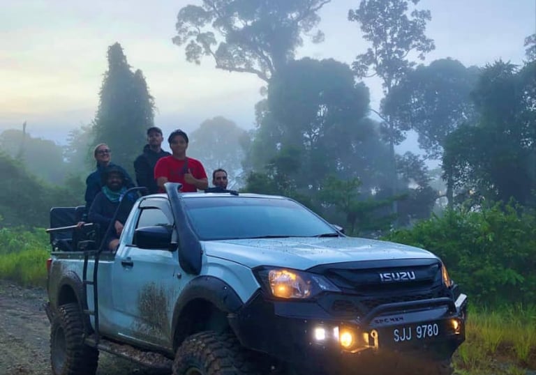 Guided Borneo jungle safari with travelers riding an off-road 4x4 truck through misty rainforest