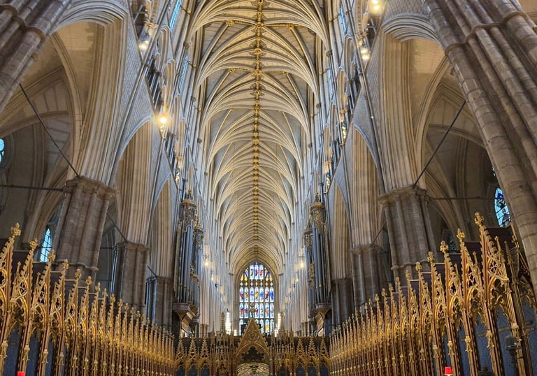 Gothic architecture of Westminster Abbey nave featuring vaulted ceilings and golden quire stalls.