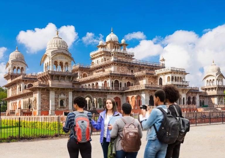 Tourists with backpacks taking photos of the historic Albert Hall Museum in Jaipur, India.