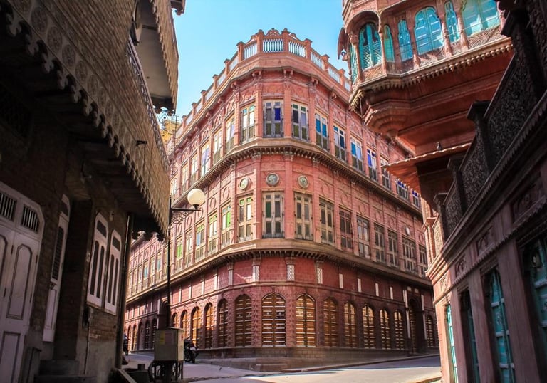 Historic pink sandstone haveli with intricate windows and traditional Rajasthani architecture in Bikaner, India.
