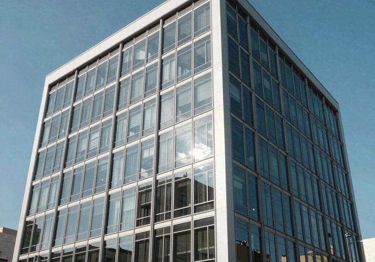 The exterior of a modern, finished corporate office building with a clean glass and steel facade, reflecting a bright blue sky, Latin American architecture.