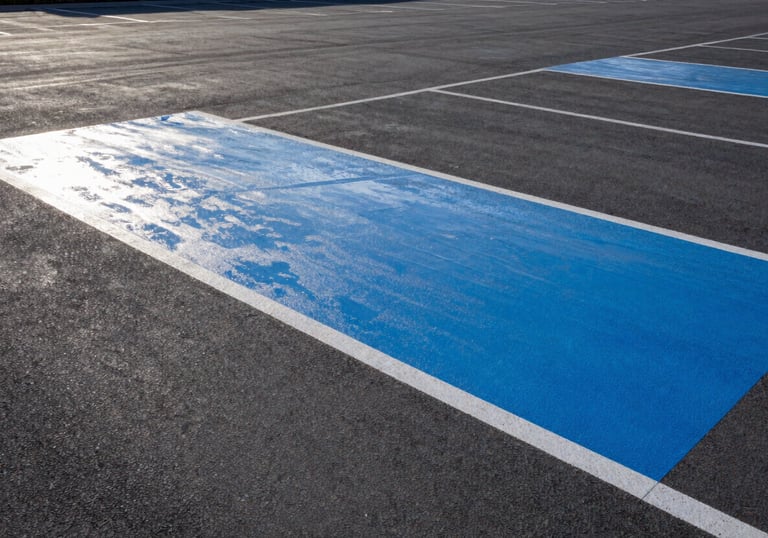 A pristine, dry commercial parking area with freshly painted steel blue markings and perfectly sealed surfaces.