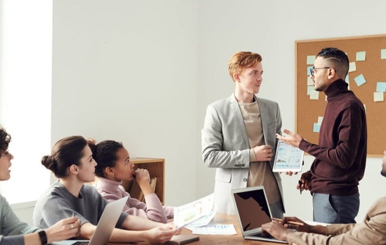 Equipo empresarial diverso colaborando en una reunión de oficina moderna con tabletas digitales y co