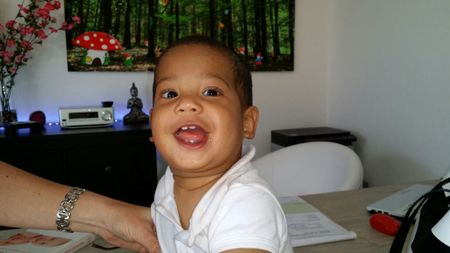 a baby boy smiling and holding a magazine