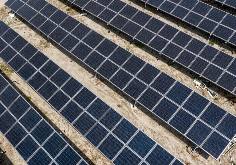 An aerial view of a solar farm or technical installation showing clean geometric rows, captured in shades of dark navy and light grey.