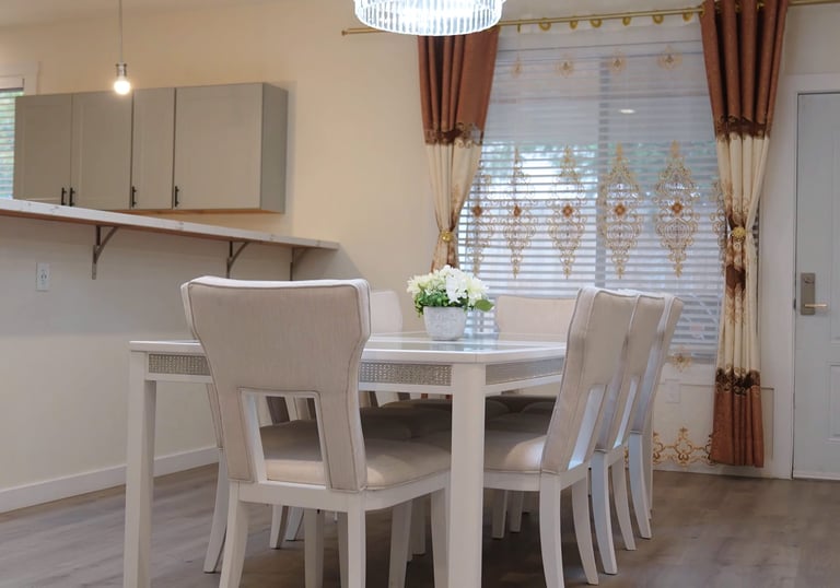 Shared dining room in adult family home with glass table and seating for resident meals.