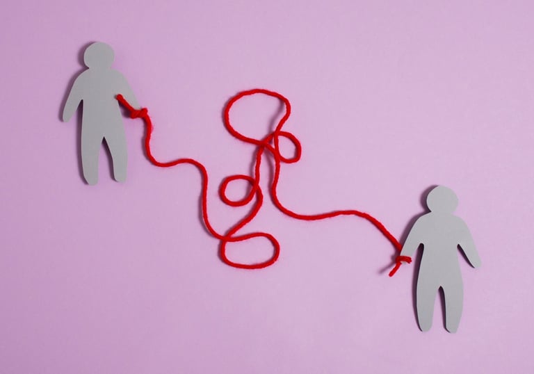Two paper human figures connected by a tangled red string representing complex emotional connections.
