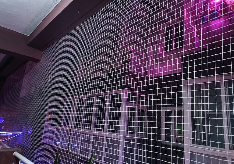 Wide shot of a spacious balcony secured with tightly woven safety nets, overlooking a bustling Banga