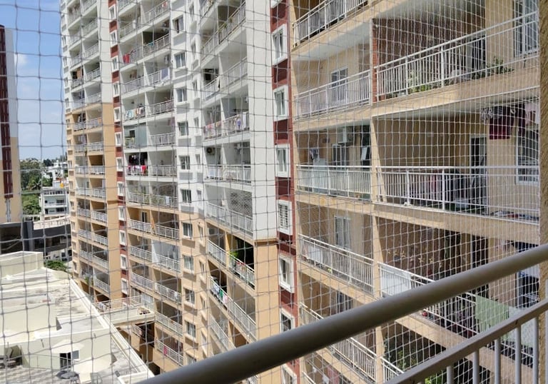 Wide shot showing a balcony fully covered with a fine mesh pigeon net, blending seamlessly with the