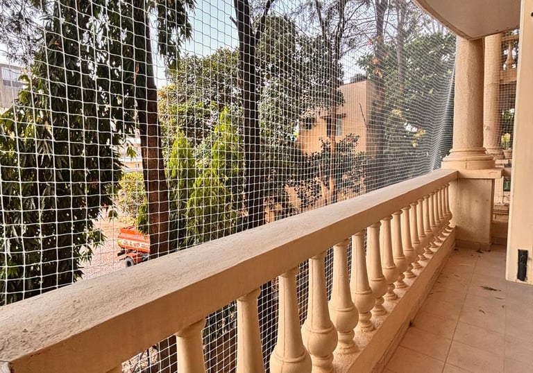 Wide shot showing a balcony fully enclosed with fine mesh pigeon netting, sunlight filtering through