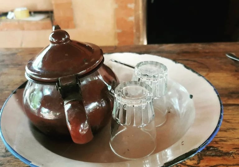 Une théière et deux verres posés sur une table en bois, créant une ambiance chaleureuse et conviviale.