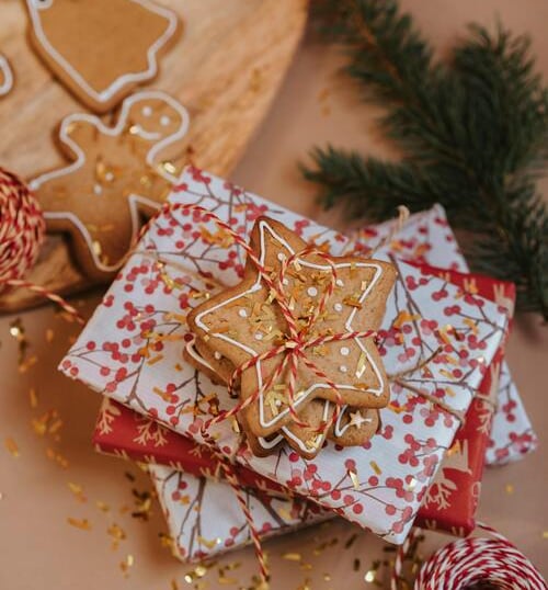 Galletas de estrella amarradas sobre regalos de navidad