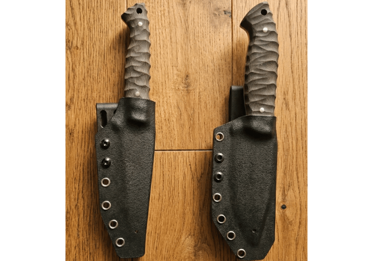 Two custom fixed blade tactical knives in black Kydex sheaths on a rustic wood surface.