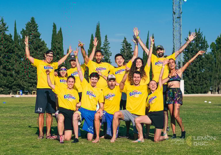 Fotografía de jugadores y jugadoras de un equipo de ultimate frisbee en un campo de césped de día