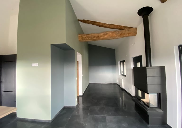 Pièce rénovée avec poutres apparentes et cheminée moderne.