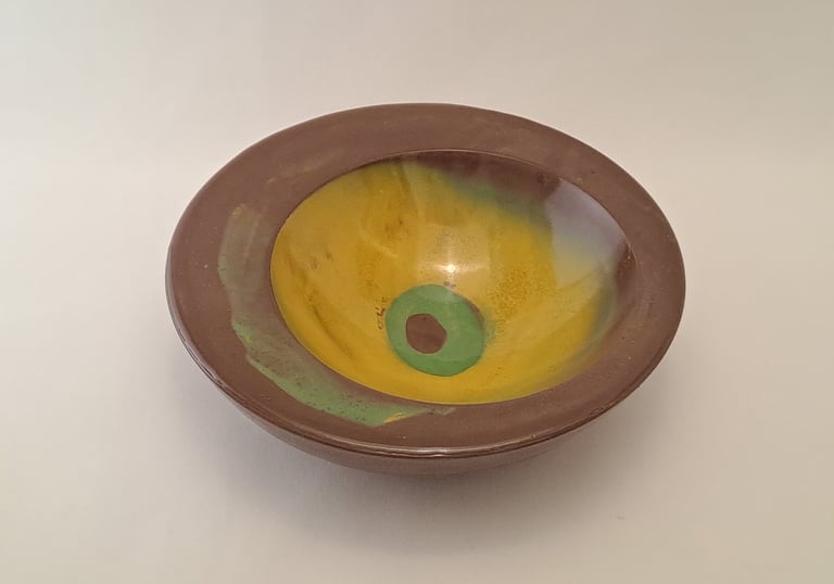 Handmade gypsum bowl featuring a brown rim and glazed yellow interior with green accents.