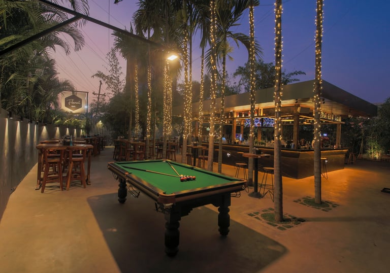 Outdoor seating and pool table at Filament Cocktail Bar Wakad with warm evening lights.