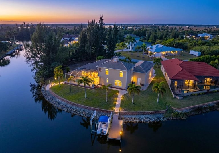 Aerial view of a luxury waterfront home with a private boat dock at sunset in Florida.