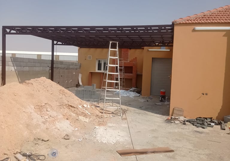 تنفيذ برجولة حديد في الرياض قيد العمل، تصميم عملي يغطي المساحة الخارجية ويوفر ظلًا قويًا.