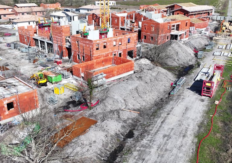 Vue aérienne d'un chantier résidentiel avec des maisons en brique rouge, des échafaudage et une grue