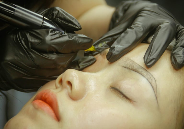 Artista profesional realizando un procedimiento de maquillaje permanente con técnica de microblading