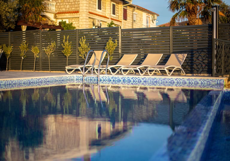 Luxurious infinity pool with sea and mountain views at sunset, lounge chairs and stone features at V
