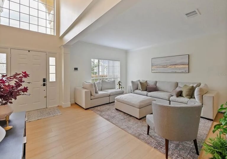 Living room with sectional seating, armchairs, and a front entry door.