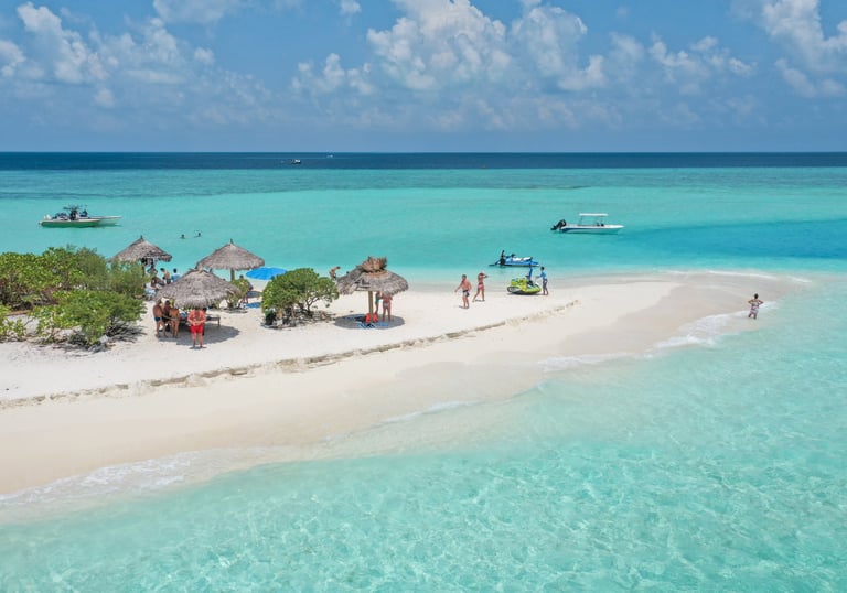 Aerial view of a tropical sandbar with turquoise water, palm umbrellas, and tourists in the Maldives.