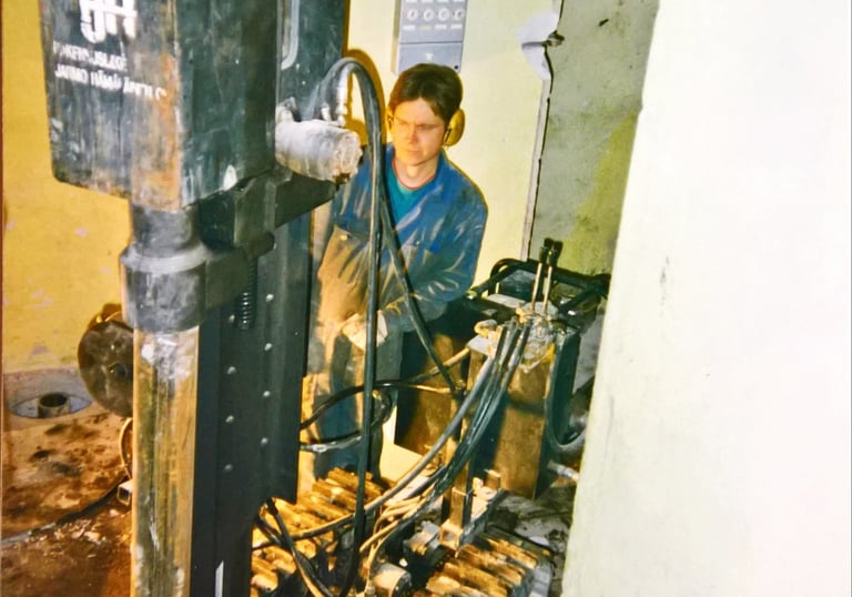 A technician operating a compact crawler mounted core drilling rig inside a building renovation site.