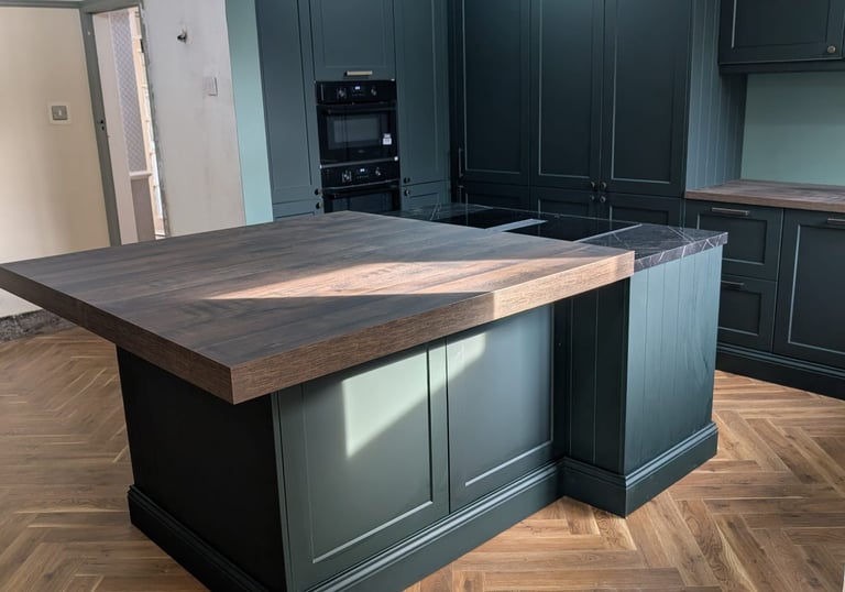 a dark green moody kitchen with a nice wooden counter top, with a side countertop of a marble