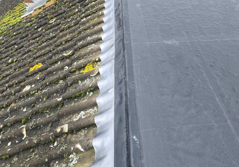 Professional EPDM rubber flat roof installation with lead flashing connected to a tiled pitched roof.
