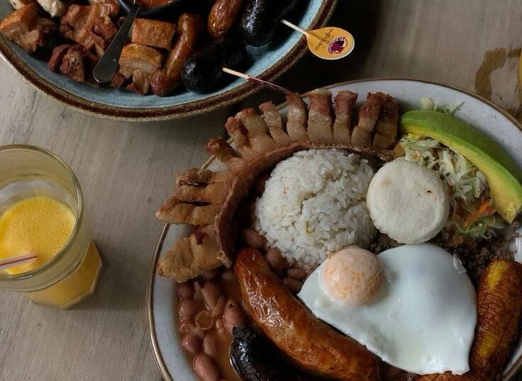Authentic Colombian Bandeja Paisa with fried egg, chorizo, crispy pork belly, beans, and rice.