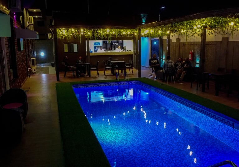 A sparkling swimming pool surrounded by lounge chairs and greenery.
