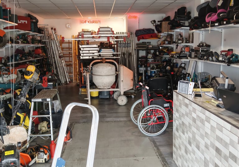 A well-stocked equipment rental shop featuring power tools, concrete mixers, and ladders on organized shelves.
