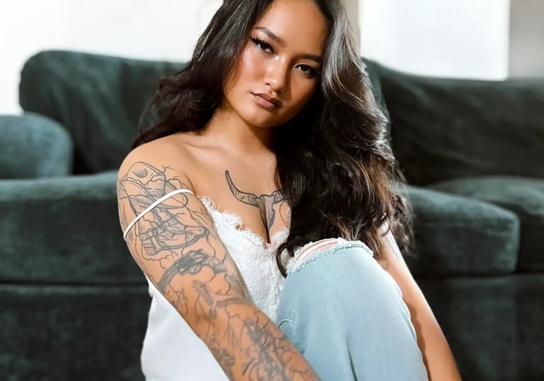 Amelia posing in jeans and a white top leaning against a couch