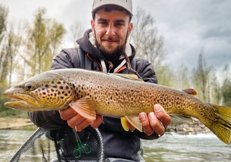 Pescador mostrando una trucha capturada en un río de León durante jornada de pesca deportiva
