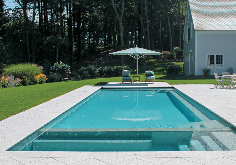 Rectangular pool with clear aqua water, light stone tiling and a shallow sun shelf for relaxed loung