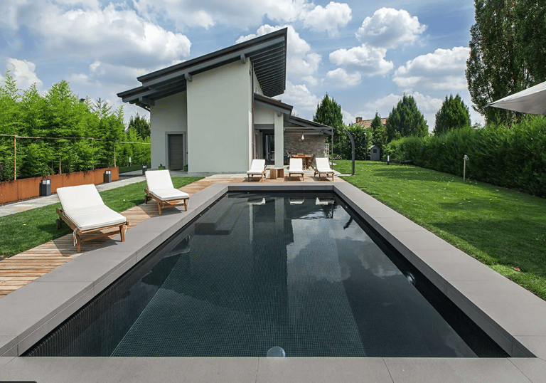 Long modern lap pool with dark teal water and grey tiling, creating a sleek, minimalist contemporary