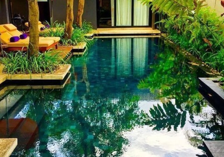 Balinese-style pool with deep green water and dark emerald mosaic tiles for a jungle-inspired finish