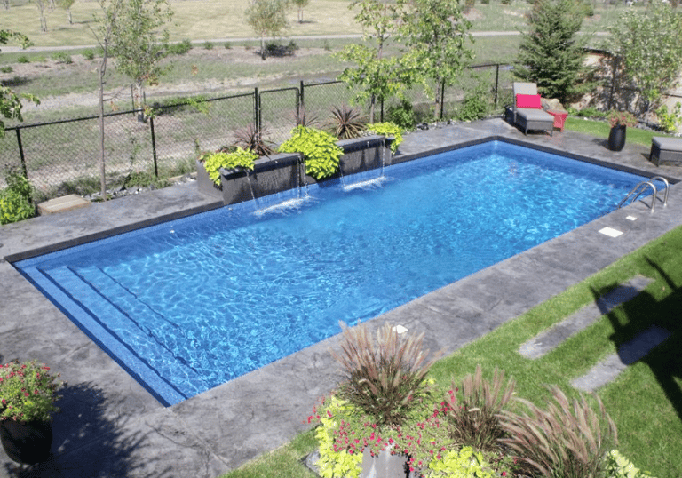 Rectangular pool with deep blue water and dark coping tiles, featuring wide entry steps along one si