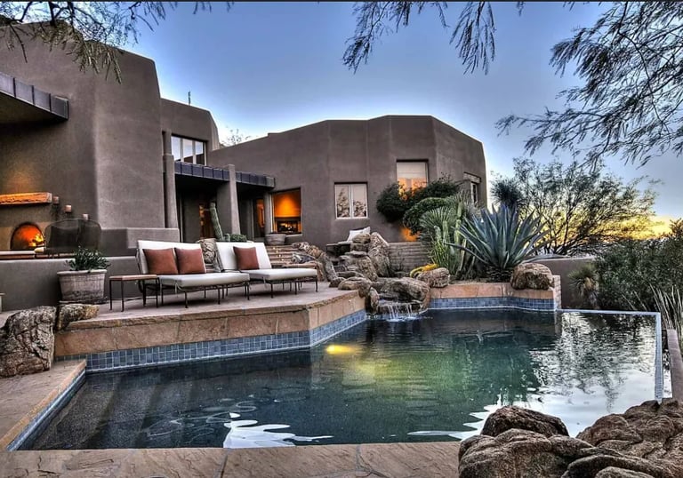 desert inspired Lagoon-style pool with, natural stone edging, and dark green–teal interior