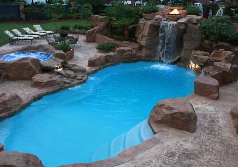 Curved lagoon pool with bright blue water, tan rock edging and light interior finish under warm ligh