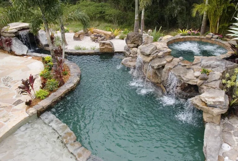 Lagoon pool with dark green water, rock waterfalls and a natural stone interior for a tropical river