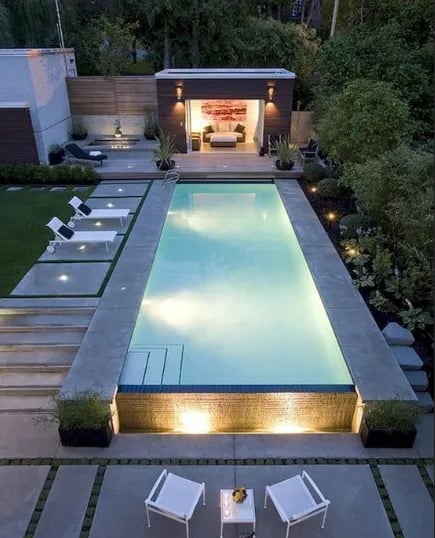 Long geometric pool with pale blue water and light stone tiling, giving a sleek modern minimalist lo