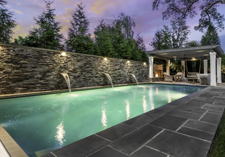 Rectangular modern pool with soft aqua water, light beige coping and dark charcoal paving.